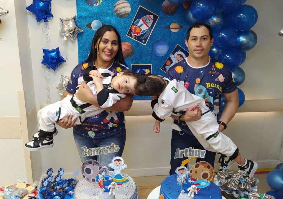 foto colorida de casal segurança gêmeos siameses no colo